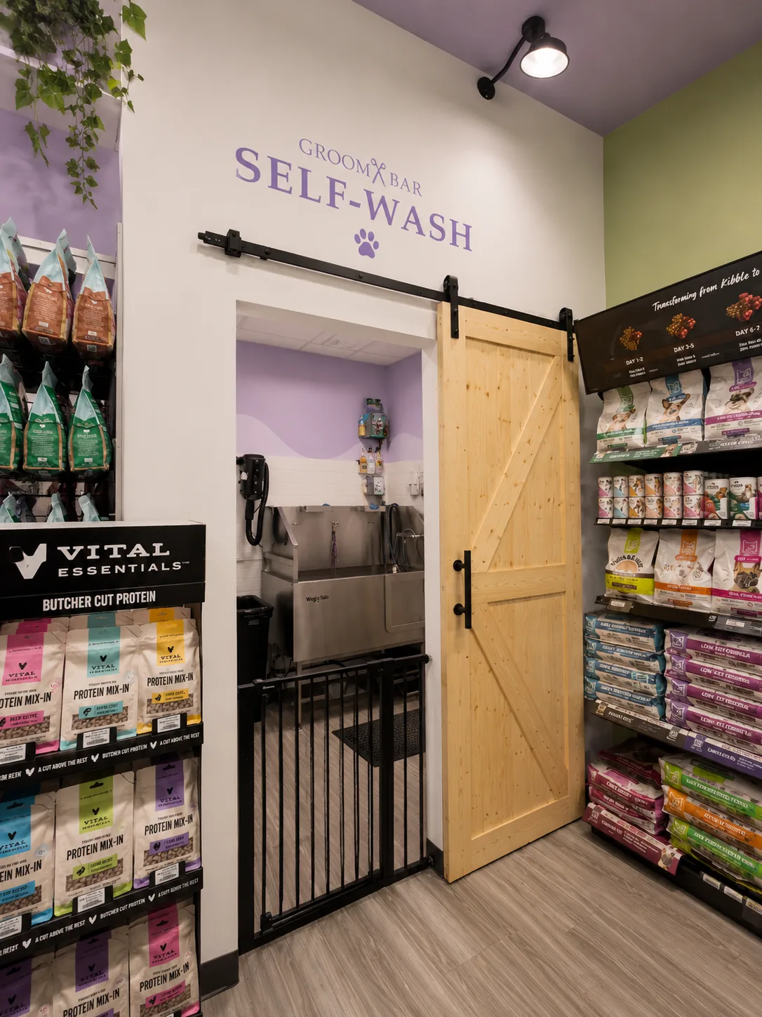 Sliding barn door entrance to the Groombar Self-Wash room, flanked by premium pet food shelves