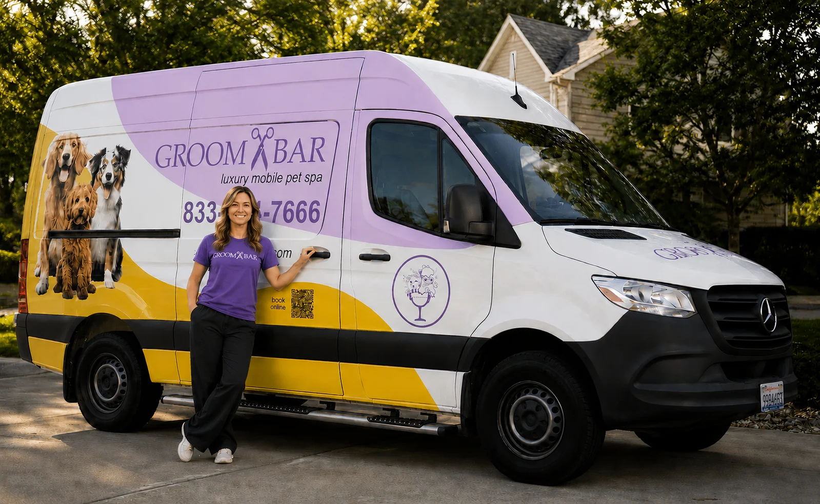 Groombar mobile groomer in purple tee standing in front of a branded luxury mobile pet spa van